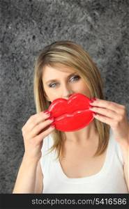 Blond woman holding novelty lips in front of her face