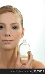 Blond woman holding perfume bottle