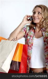 Blond woman holding shopping bags talking on cellphone