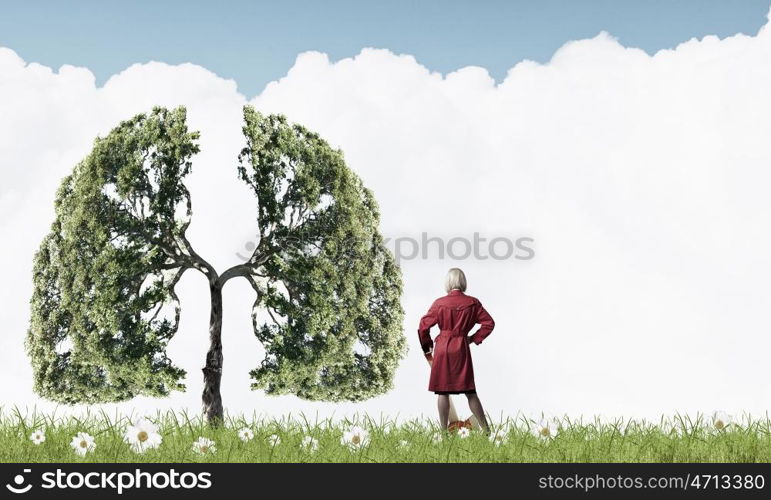 Blond woman in red coat with axe and green tree. Protect forests