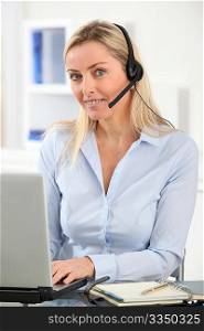 Blond woman in the office with headset on