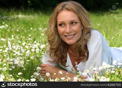 Blond woman laid in field full of daisies