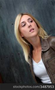 Blond woman leaning on black wall
