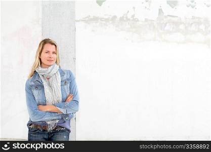 Blond woman leaning on concrete wall