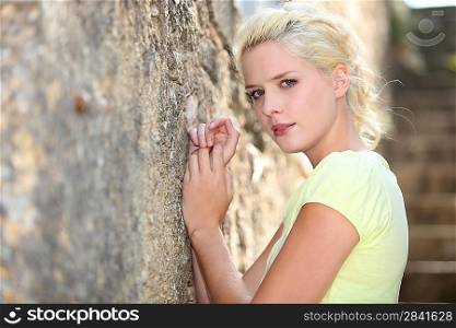 Blond woman leaning on stone wall