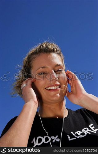 Blond woman listening to music in the sun