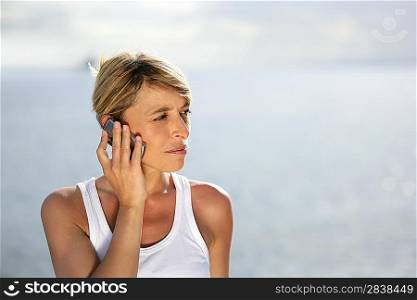 Blond woman making at call at the coast
