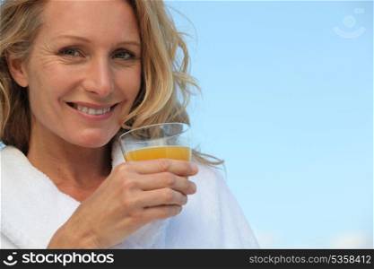 Blond woman outdoors drinking orange juice