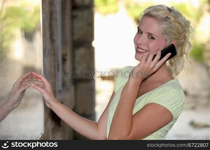 Blond woman outside restaurant on mobile telephone