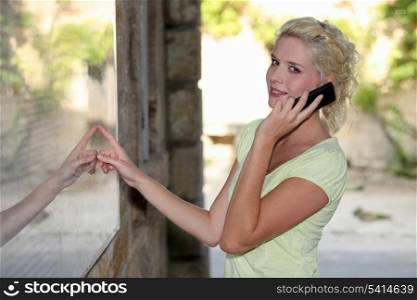 Blond woman outside restaurant using mobile telephone