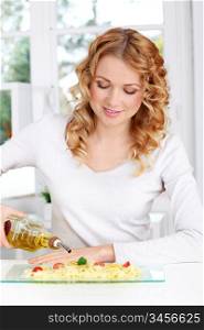 Blond woman pouring olive oil on pasta dish