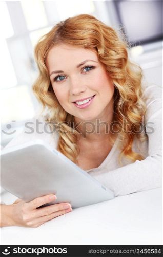Blond woman relaxing in sofa using electronic tablet
