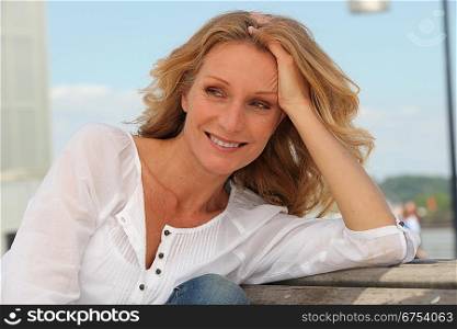 Blond woman relaxing on park bench