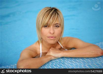 Blond woman resting by the edge of the swimming pool