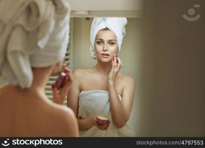 Blond woman rubbing gently a moisturising cream