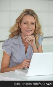 Blond woman sat at desk with laptop computer