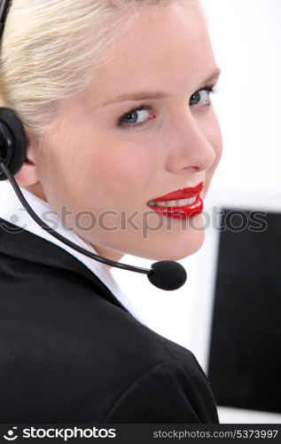 Blond woman sat by computer wearing telephone head-set