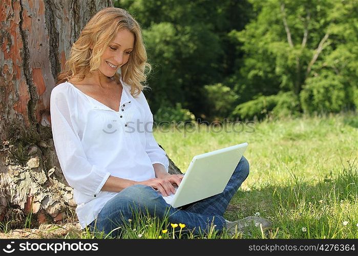 Blond woman sat by tree