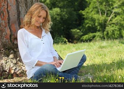 Blond woman sat by tree