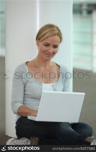 blond woman seated on floor with laptop