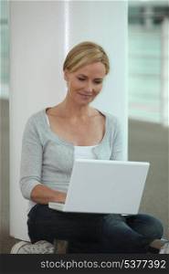 blond woman seated on floor with laptop