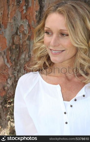 Blond woman sitting by tree
