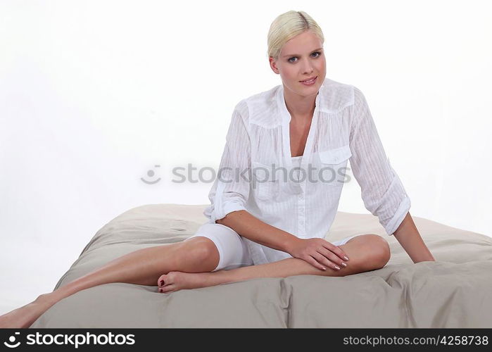 Blond woman sitting on bed