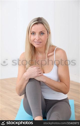 Blond woman sitting on gym mats