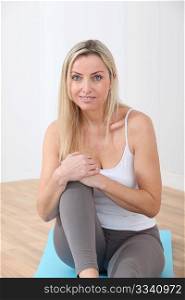 Blond woman sitting on gym mats