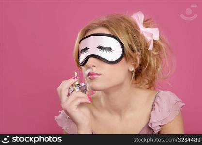 blond woman smelling perfume sleep mask blind pink background
