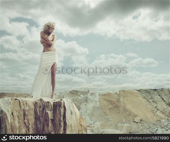 Blond woman standing on the edge of the mountain