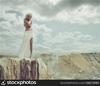 Blond woman standing on the edge of the mountain