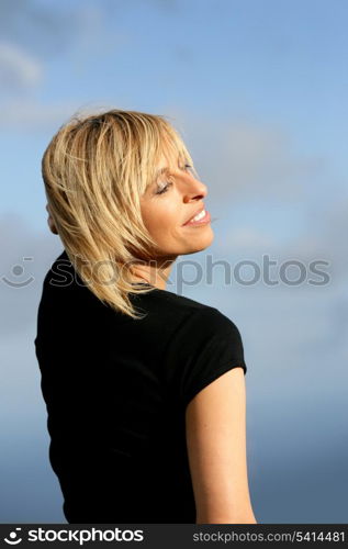 Blond woman stood outdoors on a sunny day