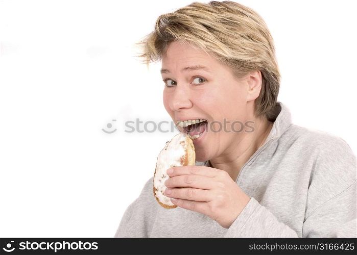 Blond woman taking a tasty bite out of a sweet bun