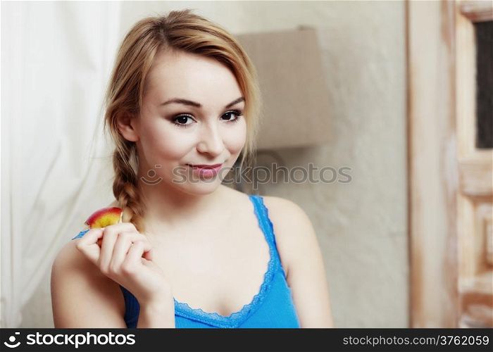 Blond woman teenage girl with braid eating apple healthy fruit. Diet and nutrition. Indoor.