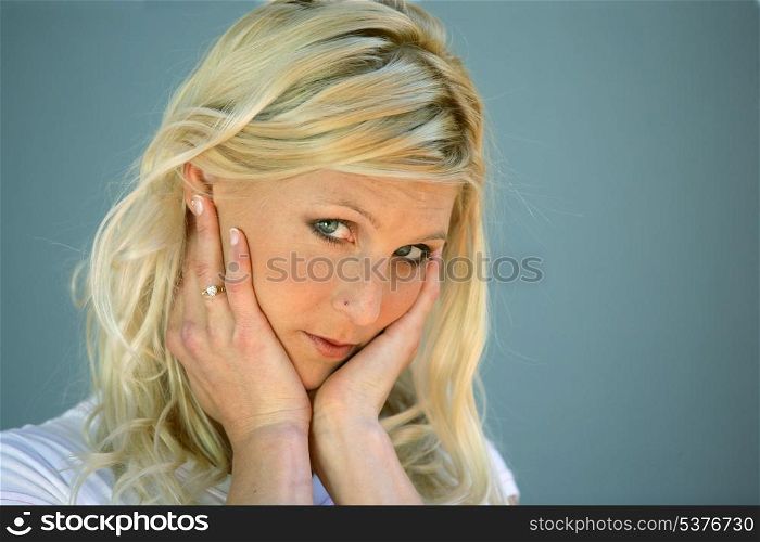 Blond woman touching her face
