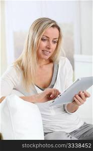 Blond woman using electronic tablet at home