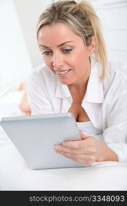 Blond woman using electronic tablet at home