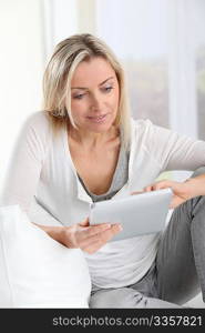 Blond woman using electronic tablet at home