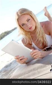 Blond woman using electronic tablet at the beach