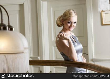 blond woman very nice , posing in elegant and keeping hotel room keys in one hand. she is smiling