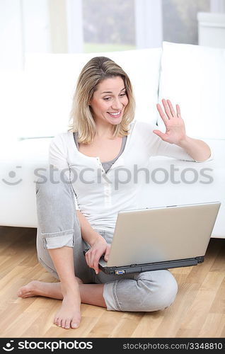 Blond woman waving at webcamera