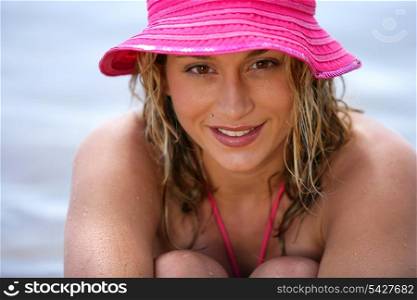 Blond woman wearing a pink hat at the beach