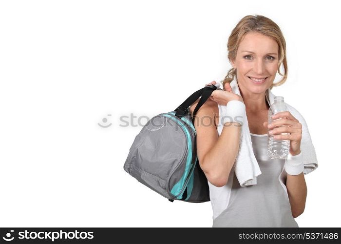 Blond woman wearing sportswear holding water bottle with bag over shoulder