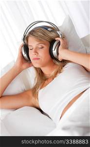 Blond woman with headphones listening to music with closed eyes