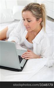 Blond woman with laptop computer in bed