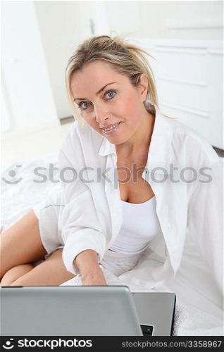 Blond woman with laptop computer in bed
