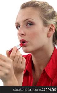 Blond worker applying lipstick