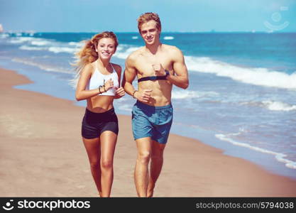 Blond young couple running on the beach in summer vacation