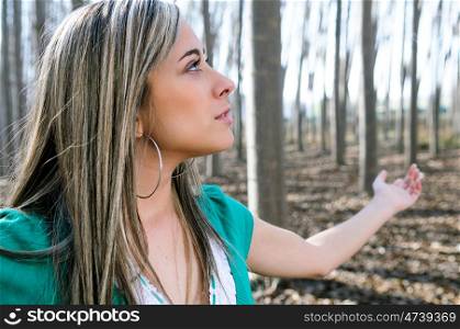 Blond young woman in poplar forest with open arms